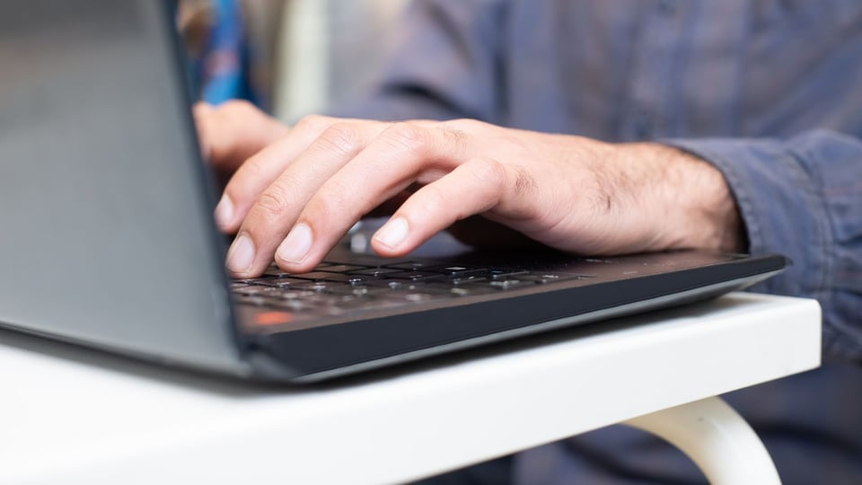 Hands typing on a laptop keyboard